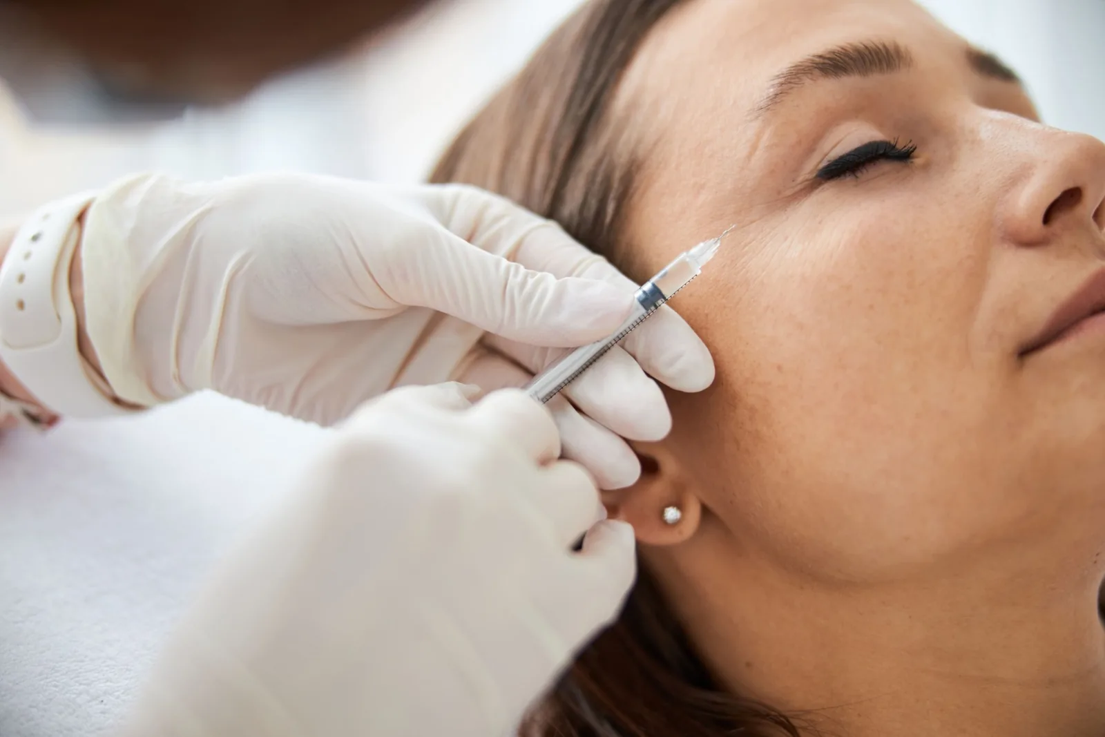 Practitioner giving a cosmetic injection near a patient's eye area during a treatment consultation in Orlando