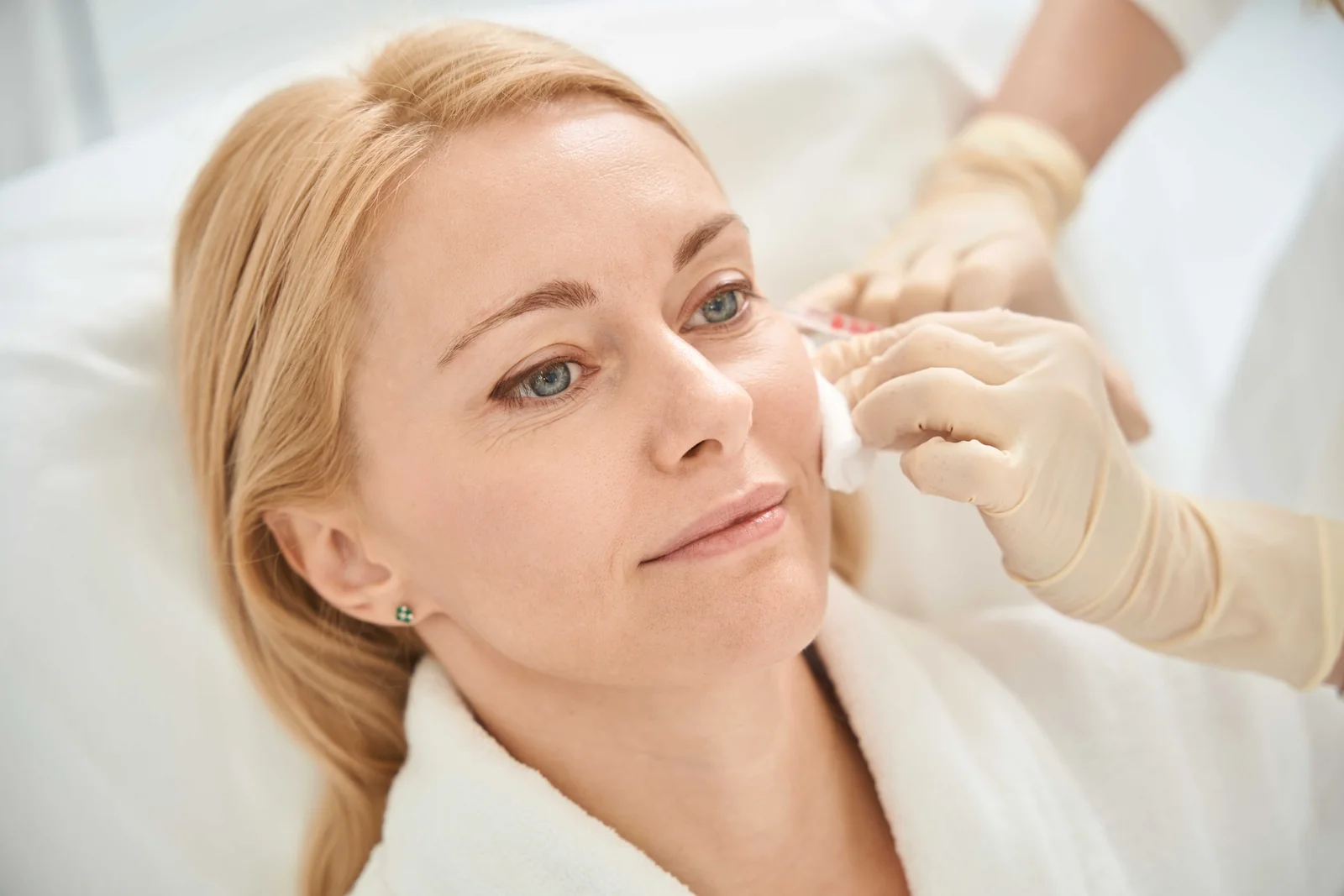 Patient receiving a facial aesthetic treatment from a gloved practitioner in East Orlando